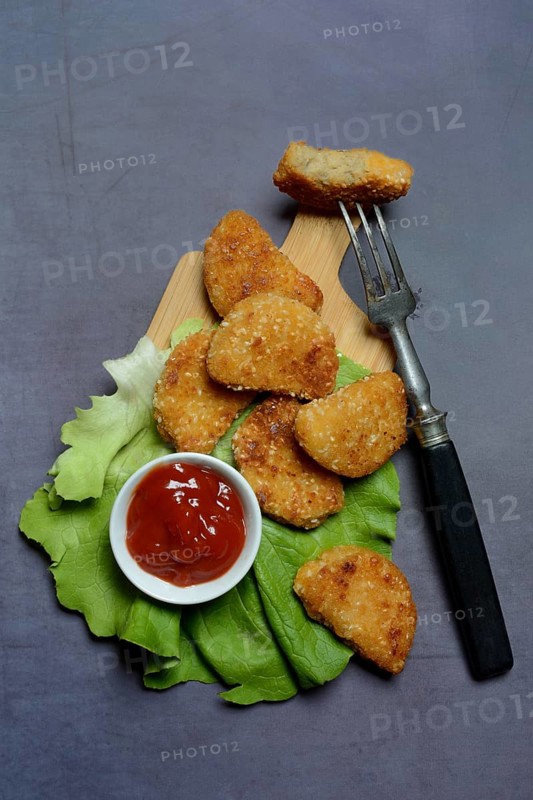 Meat substitute on wooden board and tray with ketchup