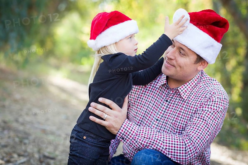 Happy father and daughter having fun wearing santa hats outdoors