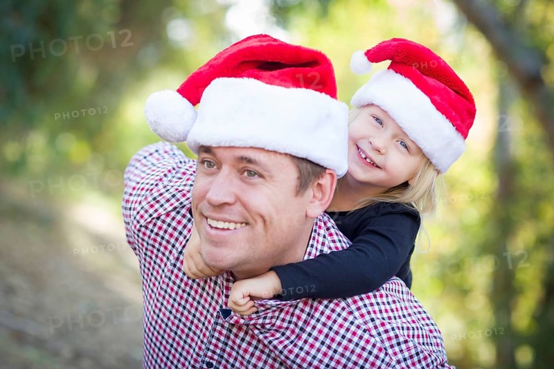 Happy father and daughter having fun wearing santa hats outdoors