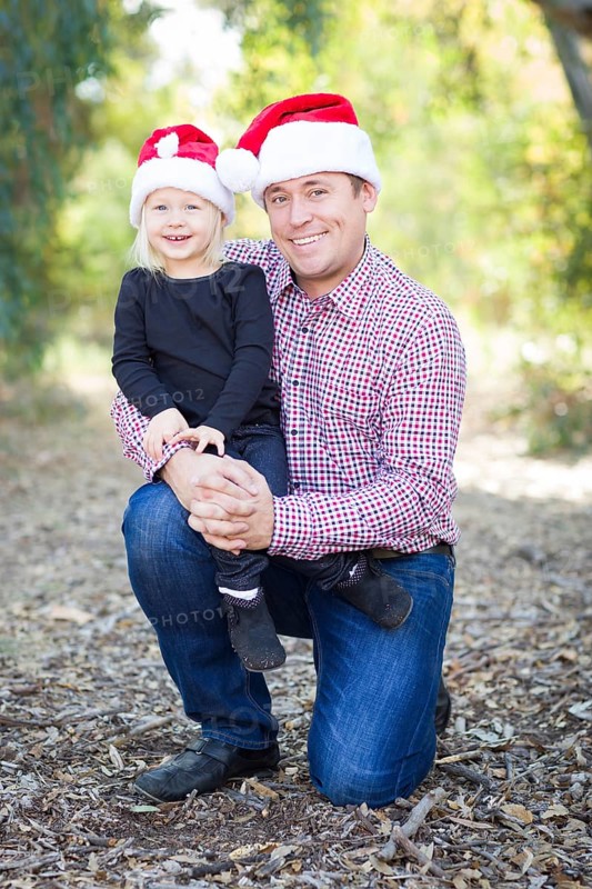 Portrait of father and daughter wearing santa hats outdoors