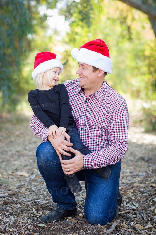 Portrait of father and daughter wearing santa hats outdoors