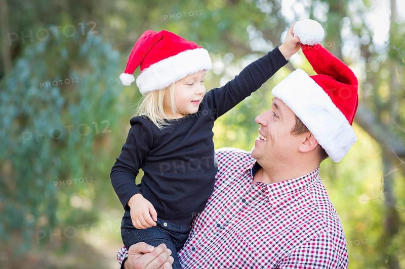 Happy father and daughter having fun wearing santa hats outdoors