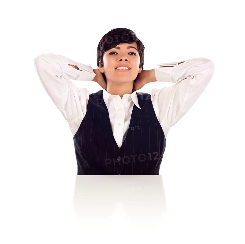 Attractive smiling mixed-race young adult female sitting at white table with hands behind her head isolated on a white background