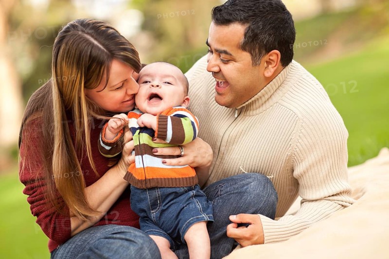 Happy mixed-race parents playing with their giggling son