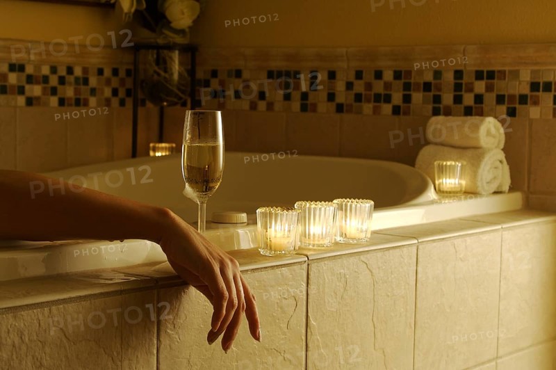 Beautiful woman in bubble bath with sparkling wine and candles surrounding her