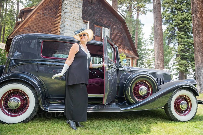 Attractive young woman in twenties outfit near antique automobile