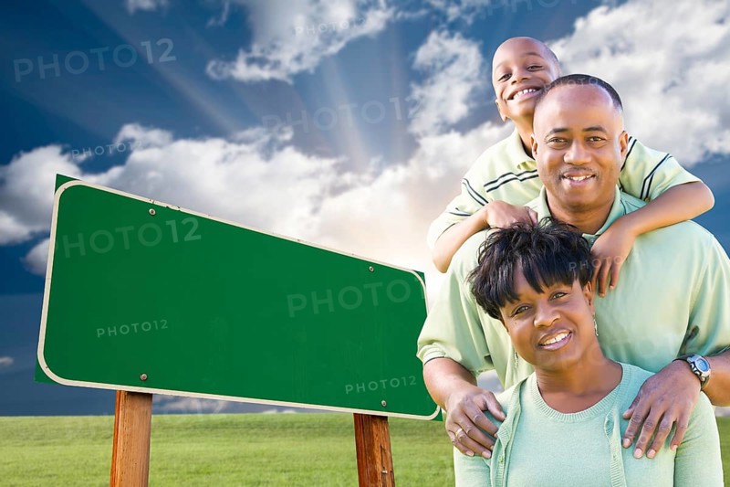 Attractive african american family in front of blank green road sign ready for your own message