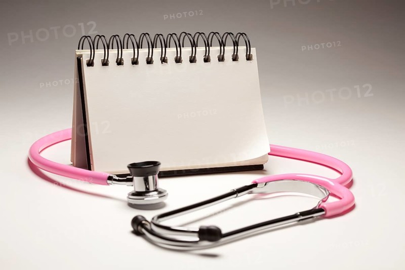 Blank spiral note pad and pink pediatric stethoscope on gradated background