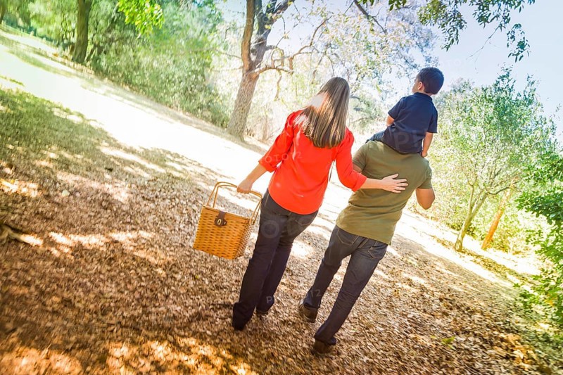 Happy mixed-race family with picnic basket enjoy a walk in the park