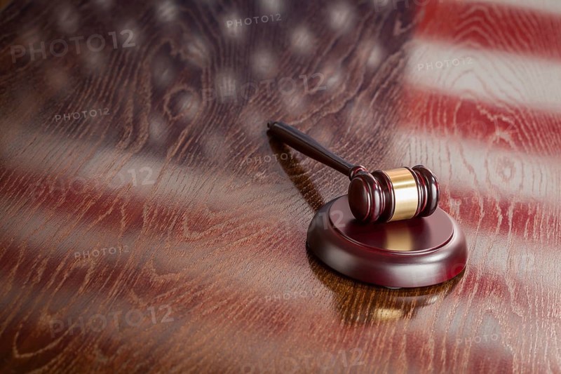 Wooden gavel resting on american flag reflecting table