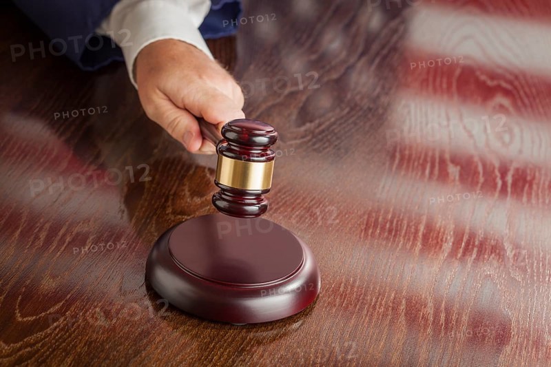Judge slams his gavel and american flag table reflection