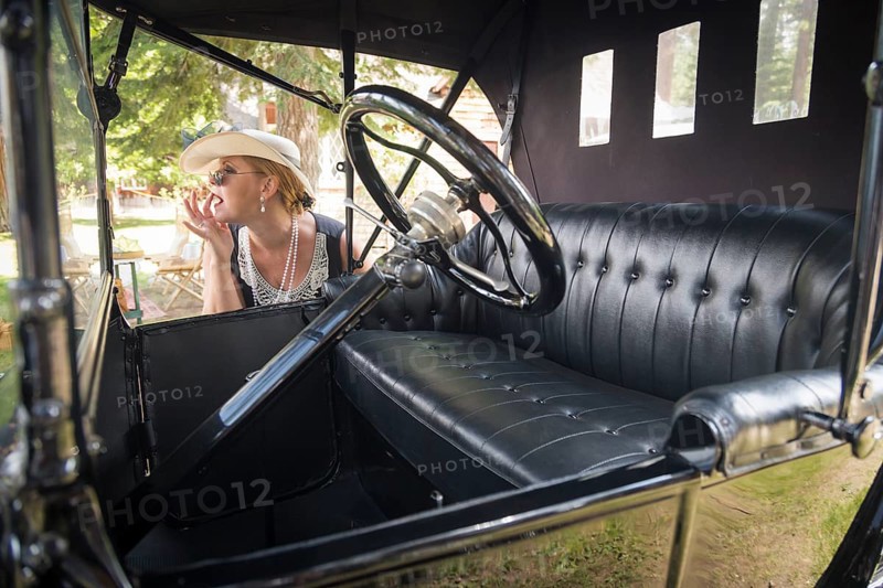 Attractive woman in twenties outfit near antique automobile