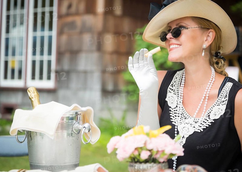 Attractive twenties dressed woman eating and drinking champagne at outdoor party