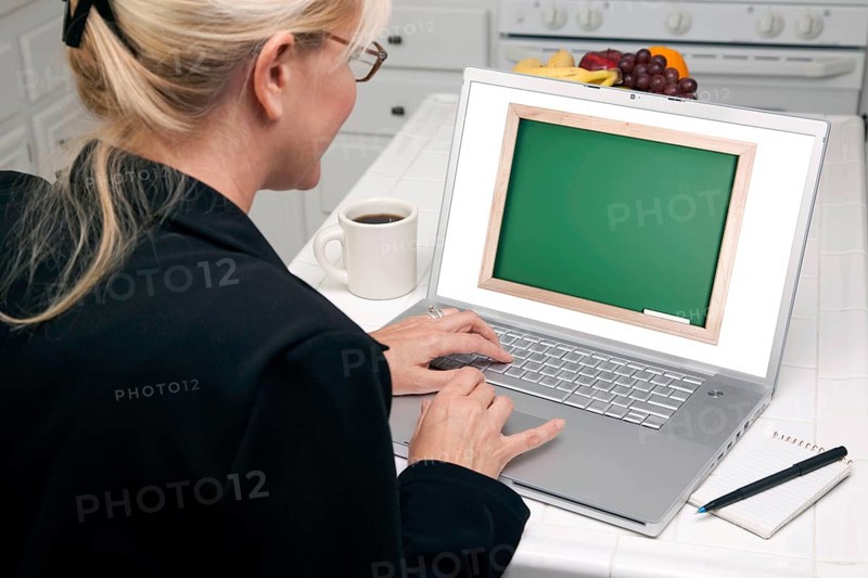 Woman in kitchen using laptop with blank chalkboard ready for you own message. screen can be easily used for your own message or picture. picture on screen is my copyright as well