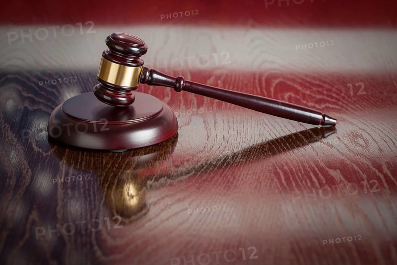 Wooden gavel resting on american flag reflecting table