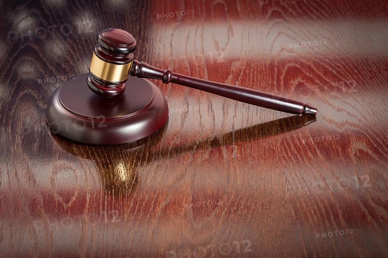 Wooden gavel resting on american flag reflecting table