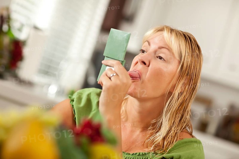 Blonde woman sticking her tongue out at herself in a compact mirror