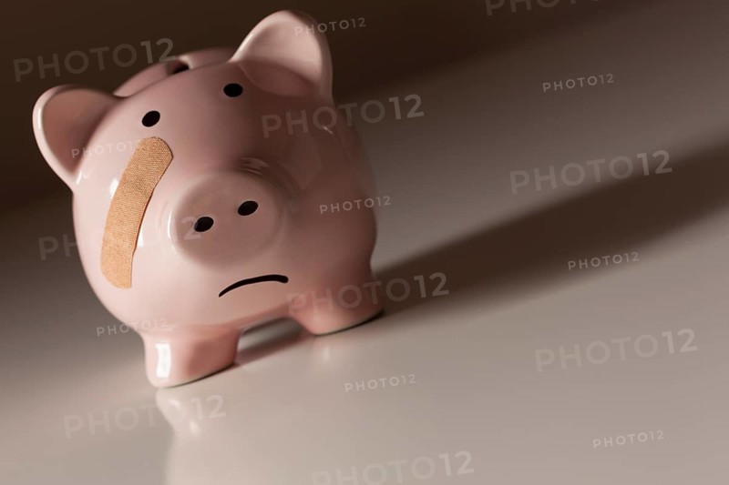 Piggy bank with bandage on face on dramatic gradated background