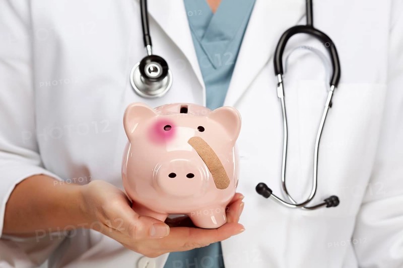 Female doctor with stethoscope holding piggy bank with bruised eye and bandage