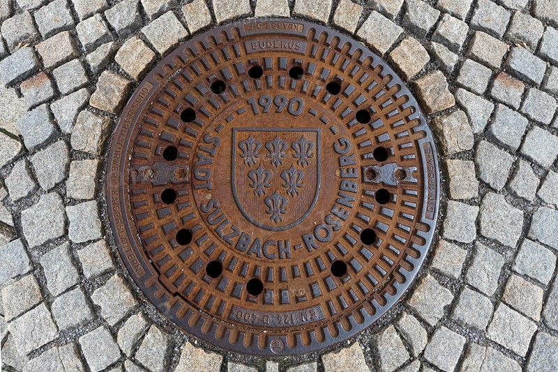 Rusty manhole cover with city coat of arms