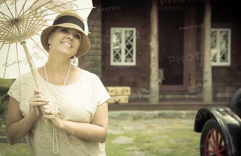 Beautiful 1920s dressed girl with parasol near vintage car