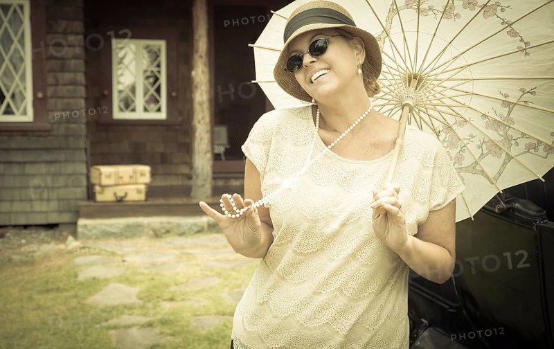 Beautiful 1920s dressed girl with parasol near vintage car