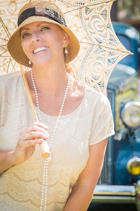Beautiful 1920s dressed girl with parasol near vintage car portrait