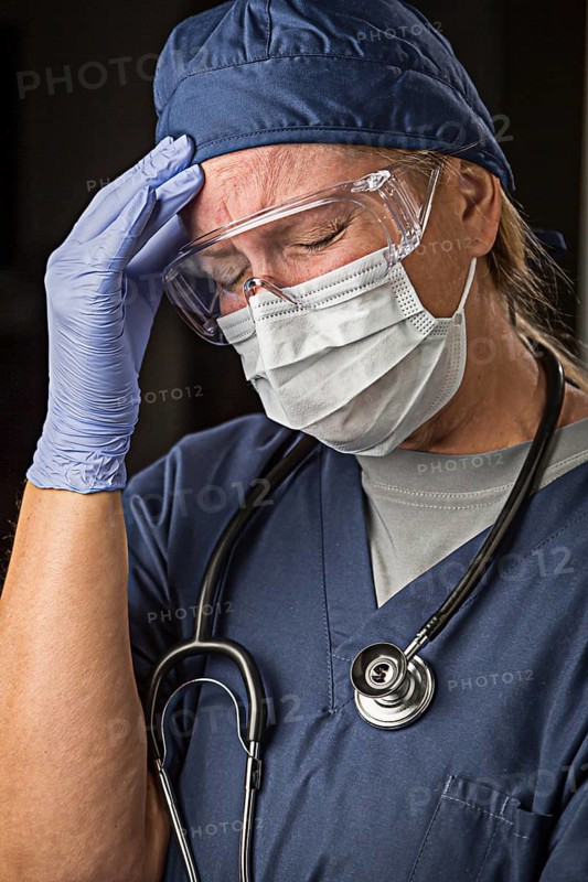 Grimacing female doctor or nurse wearing protective facial wear and surgical gloves