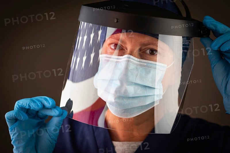 American flag reflecting on female medical worker wearing protective face mask and shield