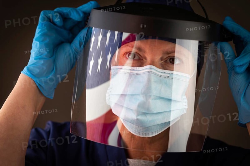 American flag reflecting on female medical worker wearing protective face mask and shield