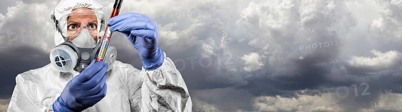Female doctor or nurse in hazmat gear holding positive coronavirus test tube cloudy sky banner