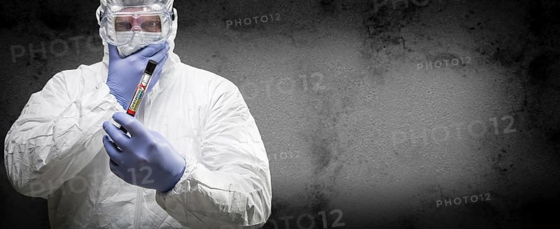 Male doctor or nurse in hazmat gear holding positive coronavirus test tube banner