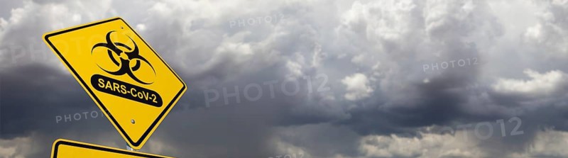 Bio-hazard symbol with sars-cov-2 coronaravirus yellow road sign against ominous stormy cloudy sky