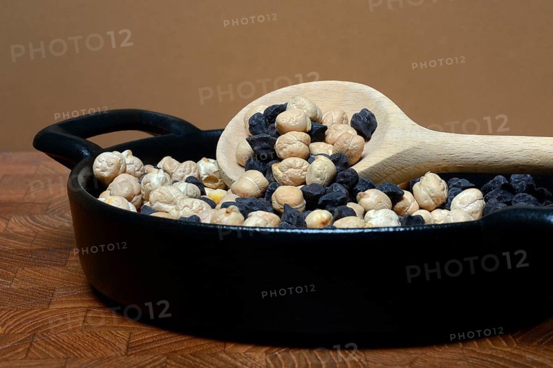 Light and black chickpeas in pot with cooking spoon