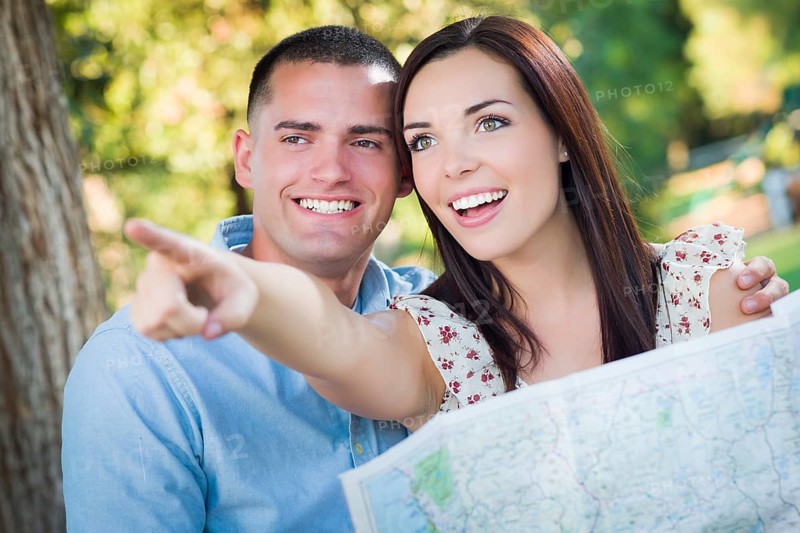 Happy mixed-race couple looking over A map and the sites outside together