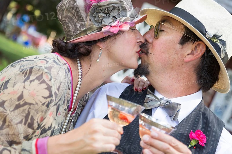 Attractive mixed-race couple dressed in 1920's era fashion sipping champagne
