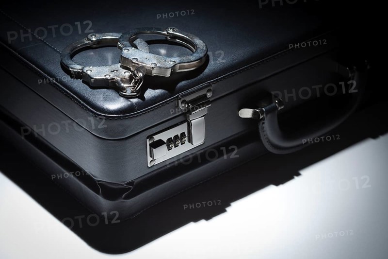 Pair of handcuffs and briefcase under spot light abstract