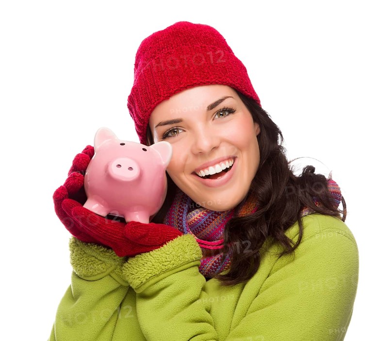 Happy smiling mixed-race woman wearing winter clothing holding piggybank isolated on white background
