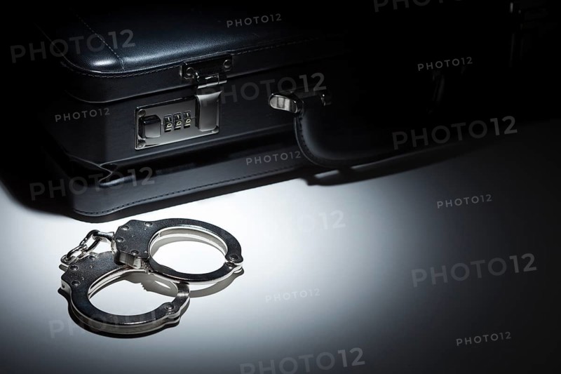 Pair of handcuffs and briefcase under spot light abstract