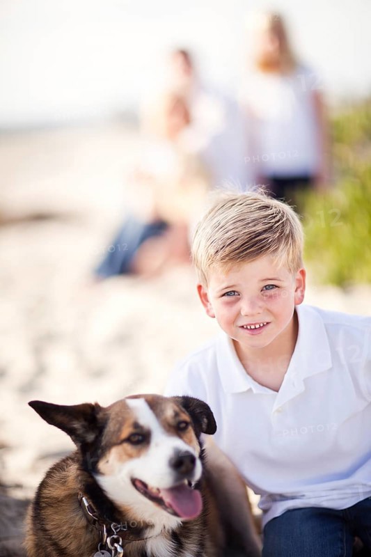 Handsome young boy playing with his dog at the beach