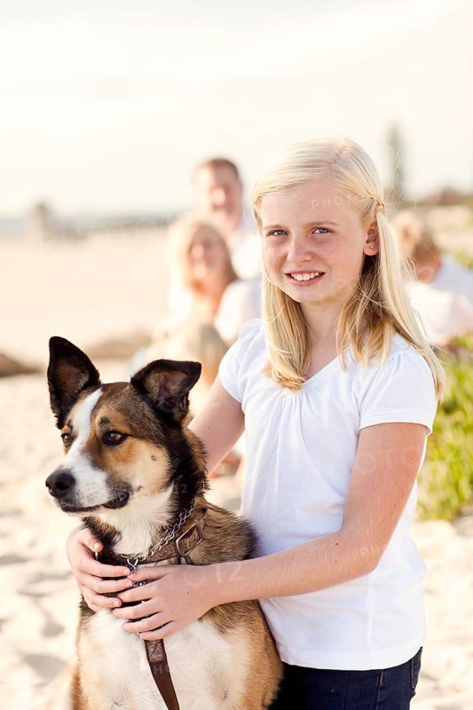 Cute girl playing with her dog at the beach