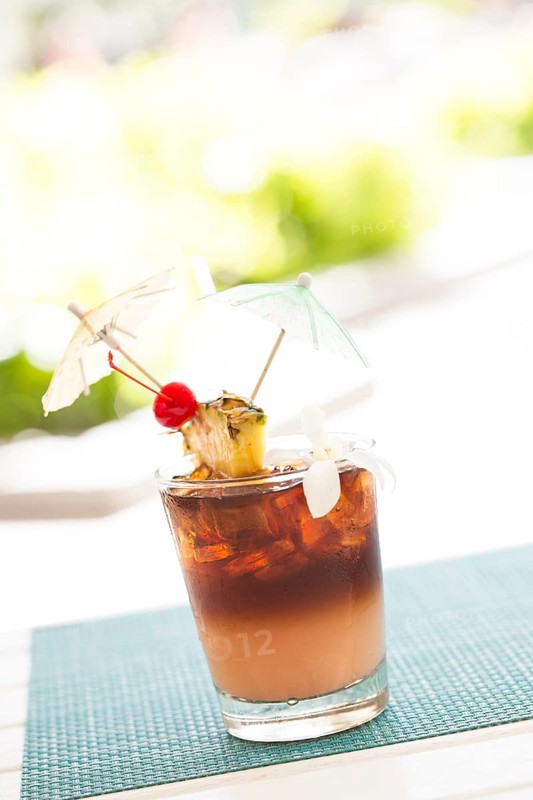 Ice cold mai tai cocktail drink with fruit and umbrellas at the bar