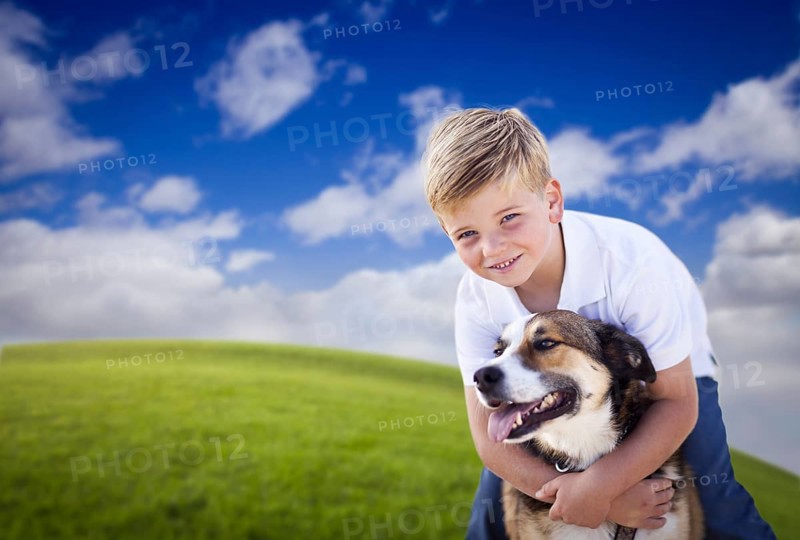 Handsome young boy playing with his dog on a lush green grass field