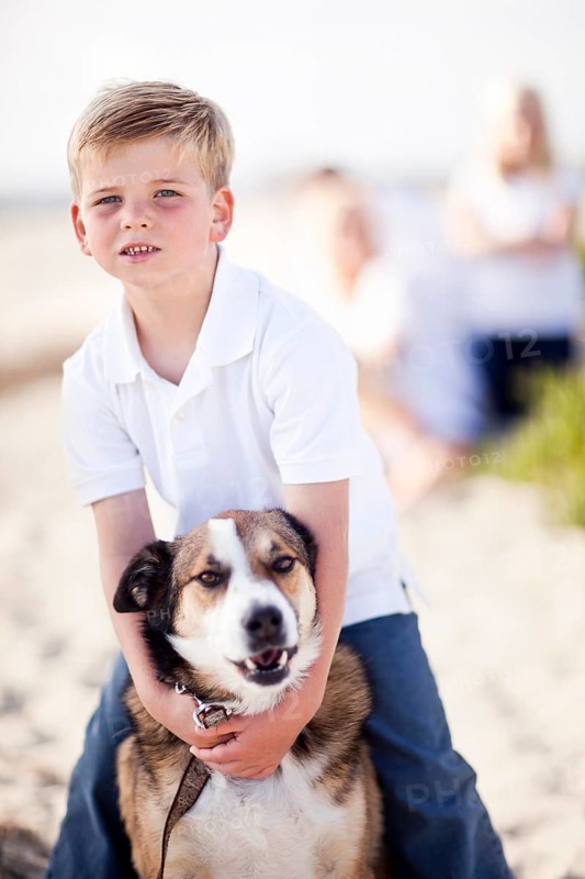 Handsome young boy playing with his dog at the beach