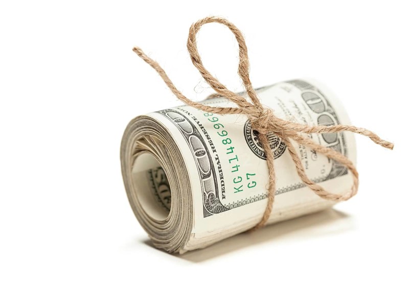 Roll of one hundred dollar bills tied in burlap string isolated on a white background