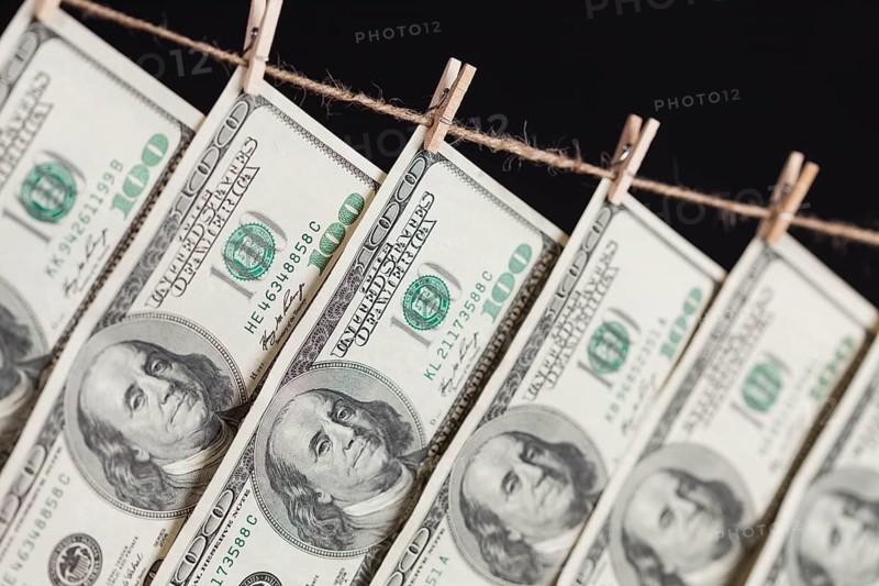 Hundred dollar bills hanging from a clothesline on a dark background