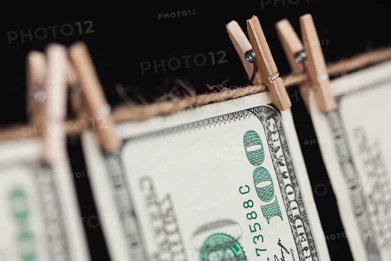 Hundred dollar bills hanging from a clothesline on a dark background