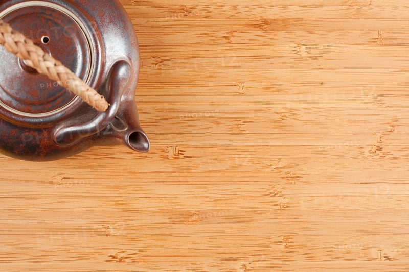Tea pot and bamboo textured surface background with plenty of room for text