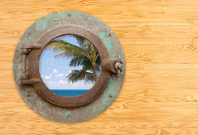 Antique porthole with tropical beach view on a bamboo wall background