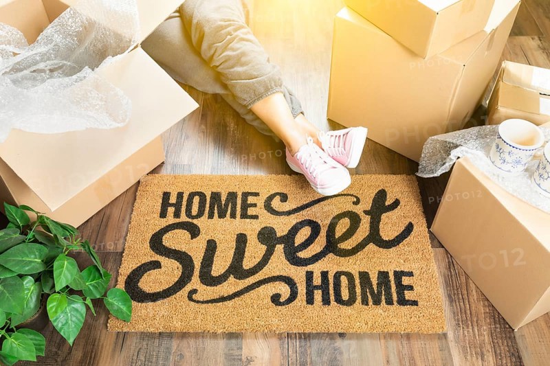Woman wearing sweats relaxing near home sweet home welcome mat